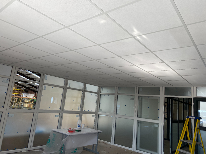 Office interior with suspended ceiling tiles and glass partition walls during installation