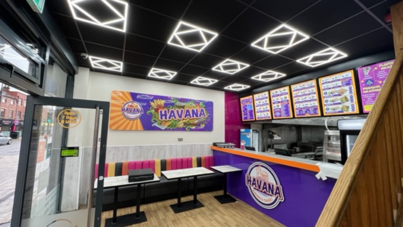 restaurant interior with modern ceiling lights, colourful seating, menu boards, and branded counter
