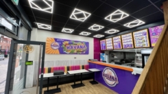 restaurant interior with modern ceiling lights, colourful seating, menu boards, and branded counter