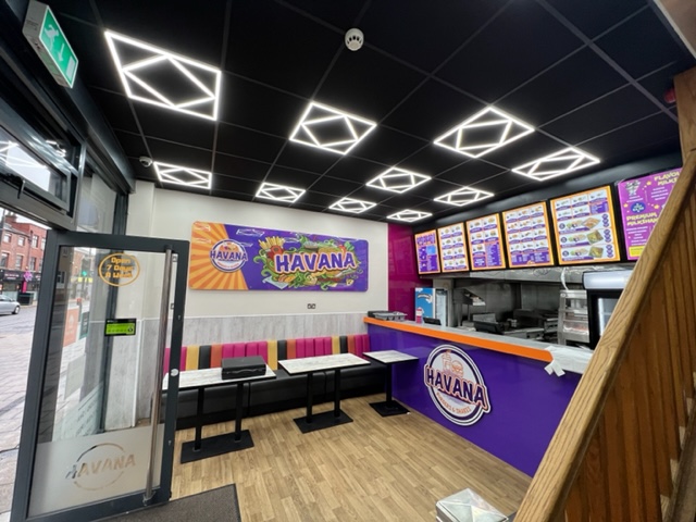 restaurant interior with modern ceiling lights, colourful seating, menu boards, and branded counter